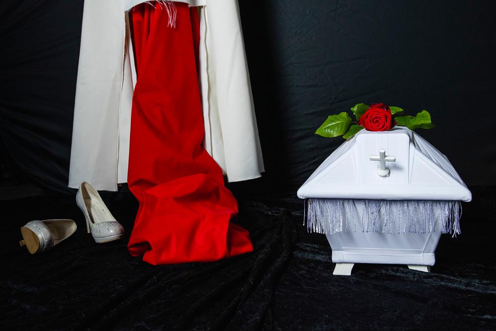 Liten vit kista, brudklänning och rött tyg. Länk till nyhet på en annan webbsida.