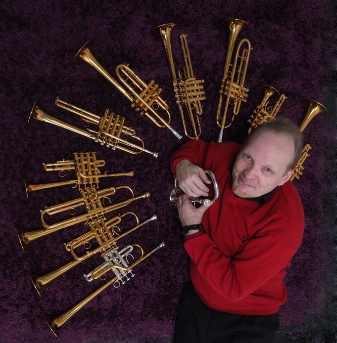 Jouko Harjanne omgiven av många trumpeter.