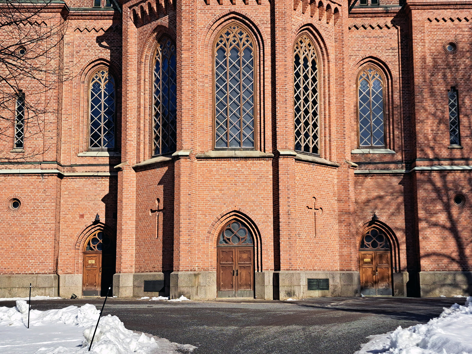 Fönster och dörrar på en röd tegelkyrka.