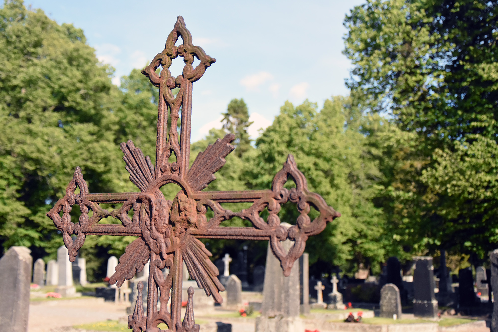 Rostigt utsirat kors på en gravgård.