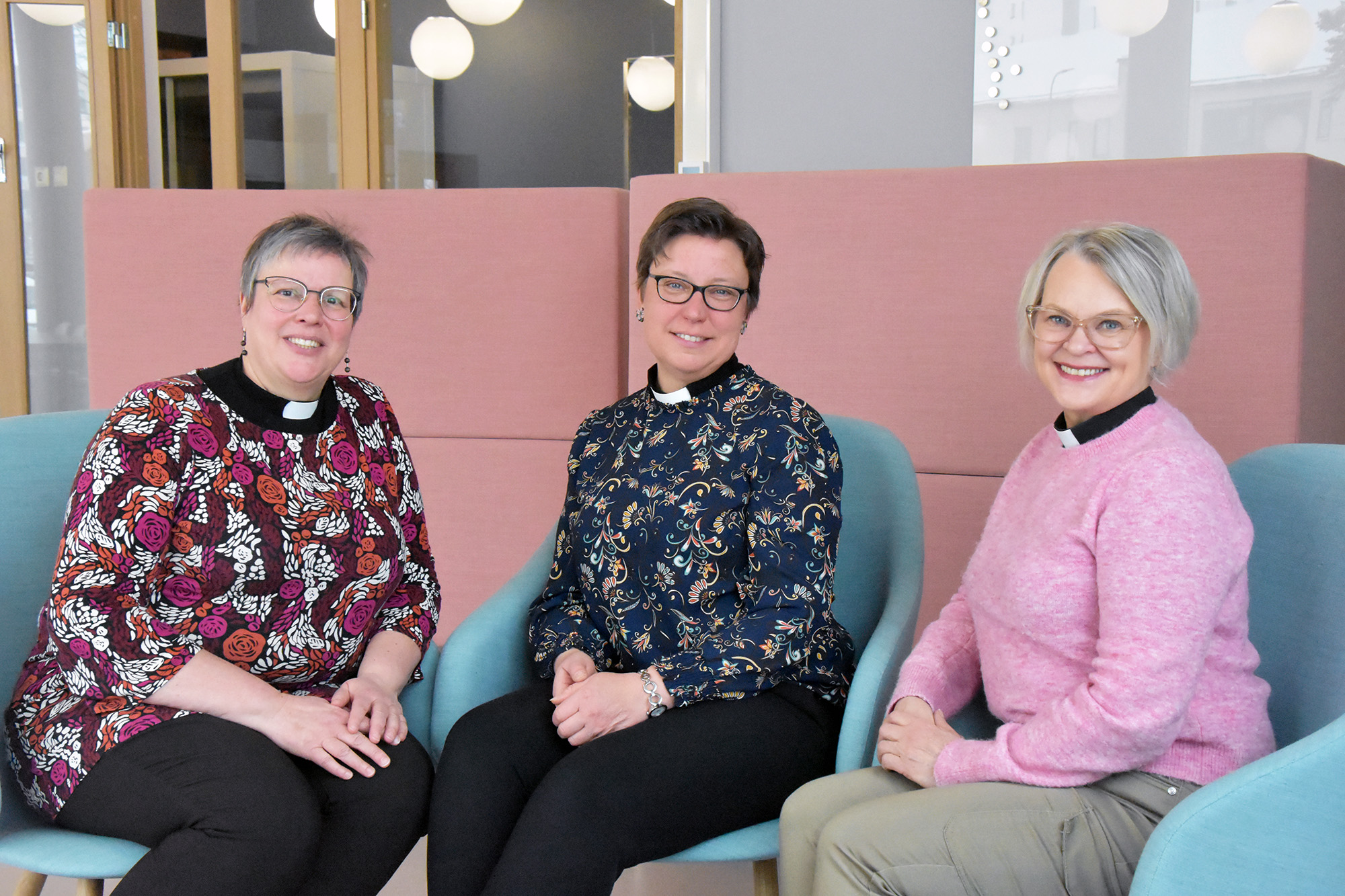 Tre kvinnor med prästkrage sitter i fåtöljer.