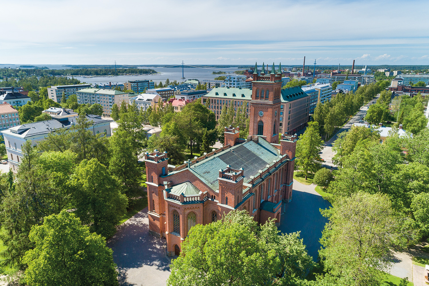 Flygbild av röd tegelkyrka i en park.