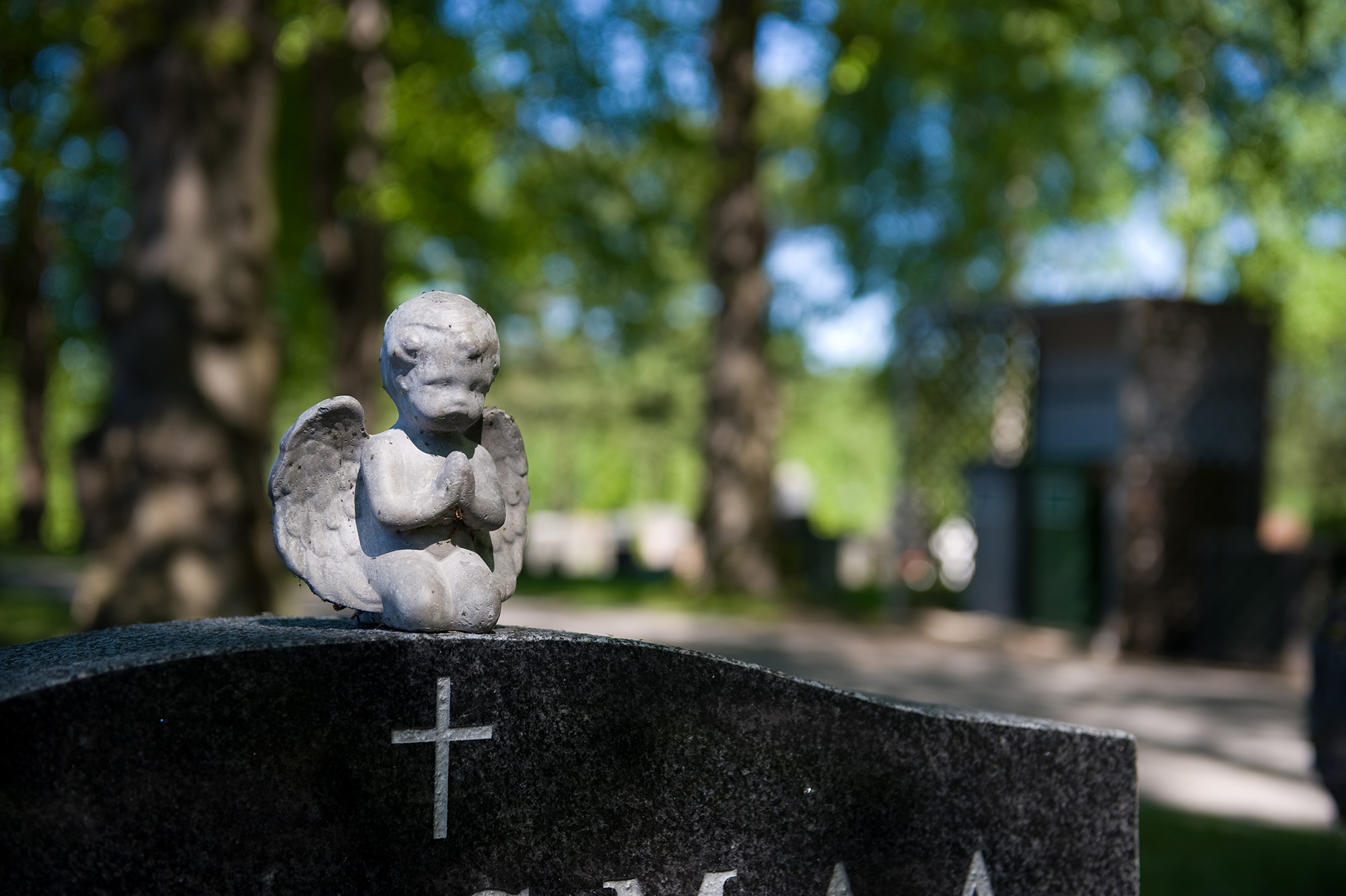 Liten staty av en ängel på en gravsten.