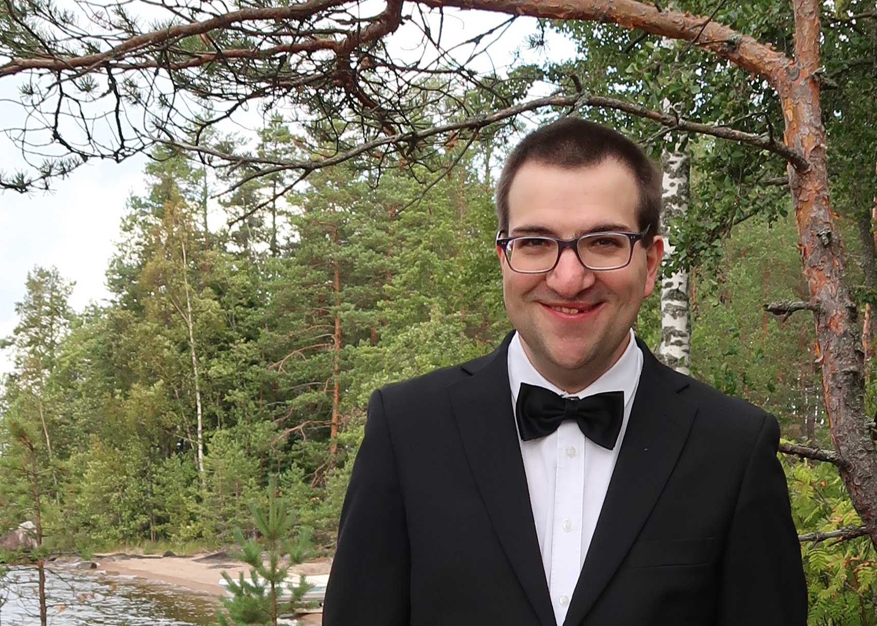 Man står utomhus, skog i bakgrunden.