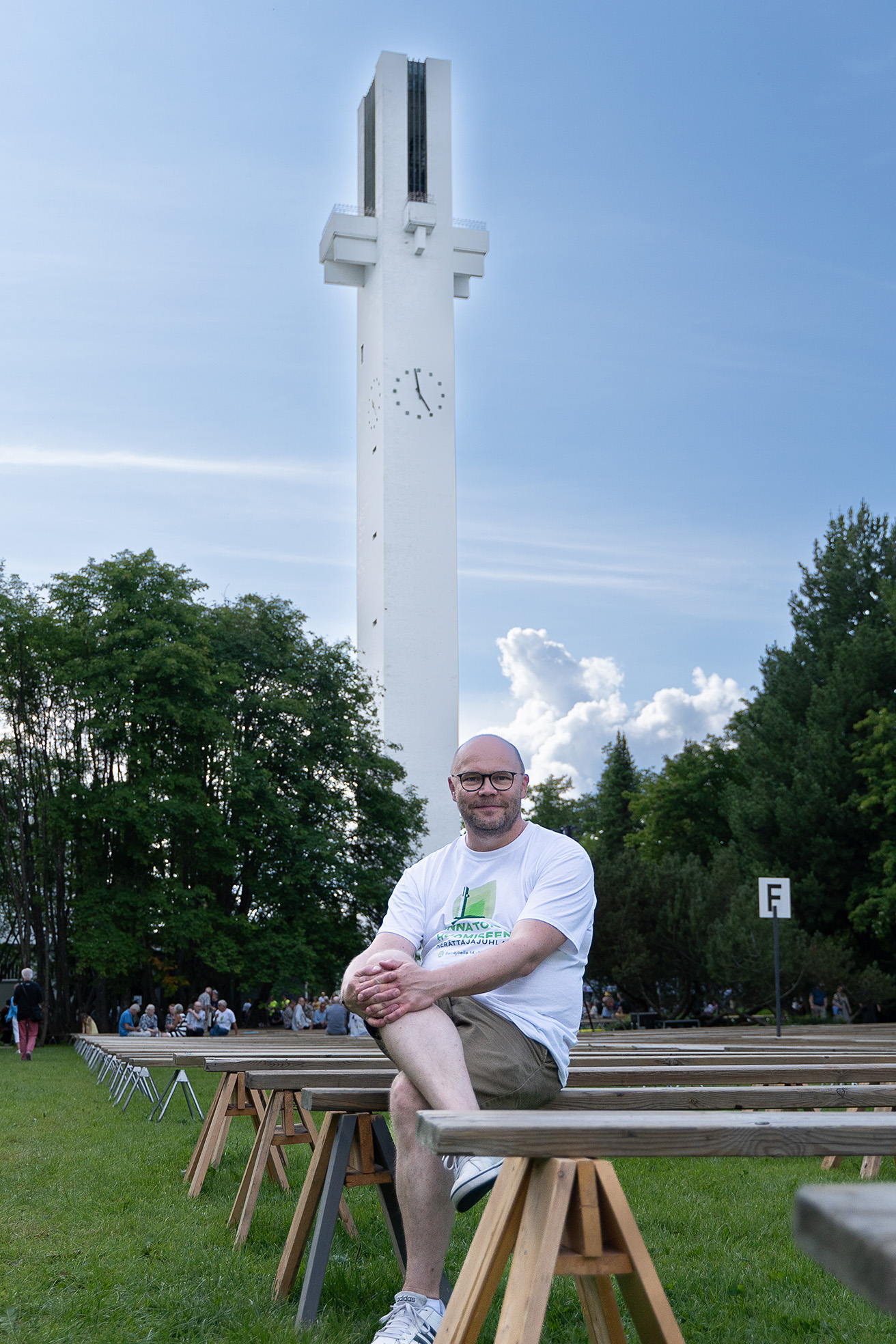 Man sitter framför en vit, hög klockstapel.